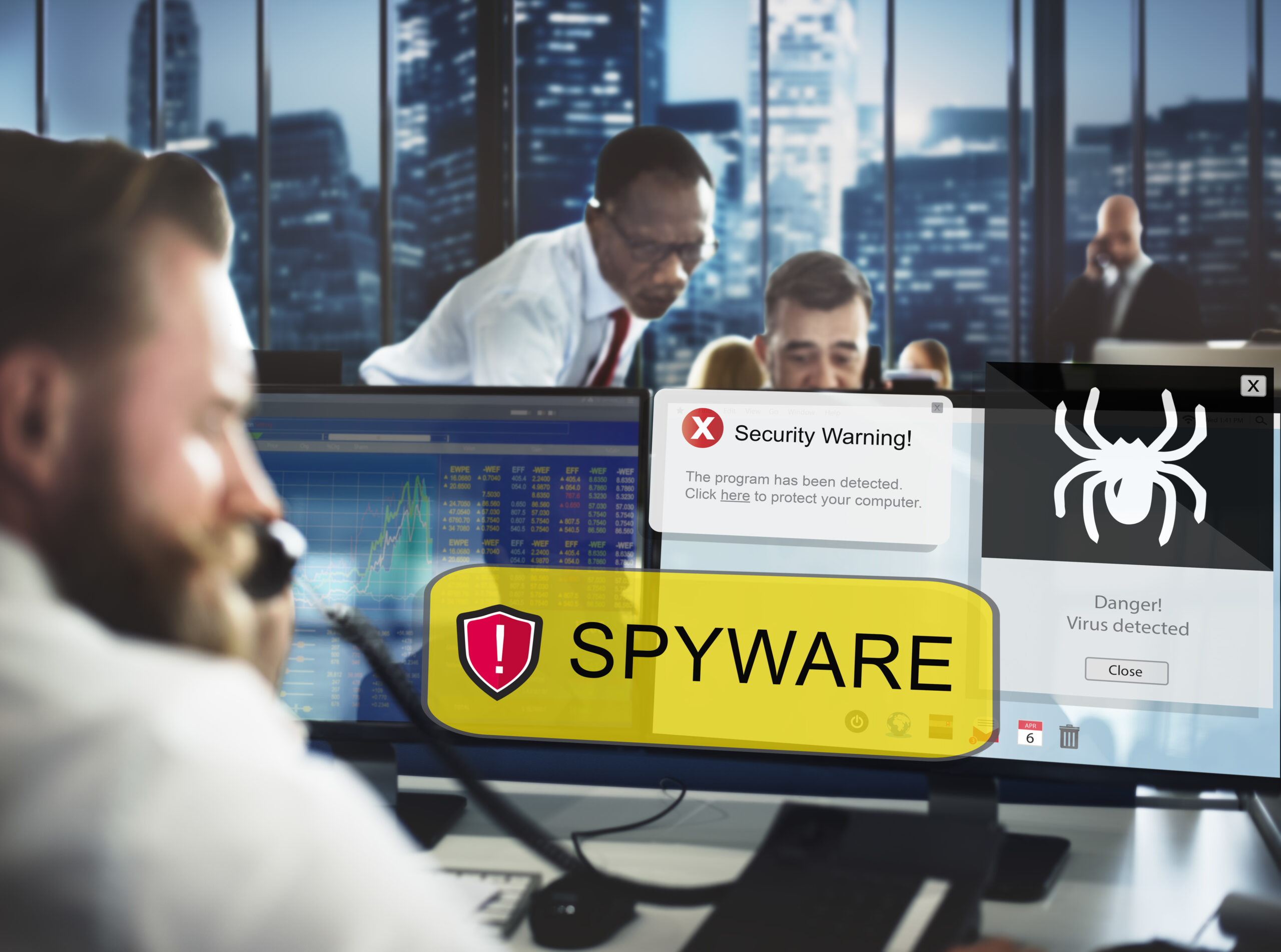 Office workers responding to security warnings on their computer screens about spyware and virus threats.