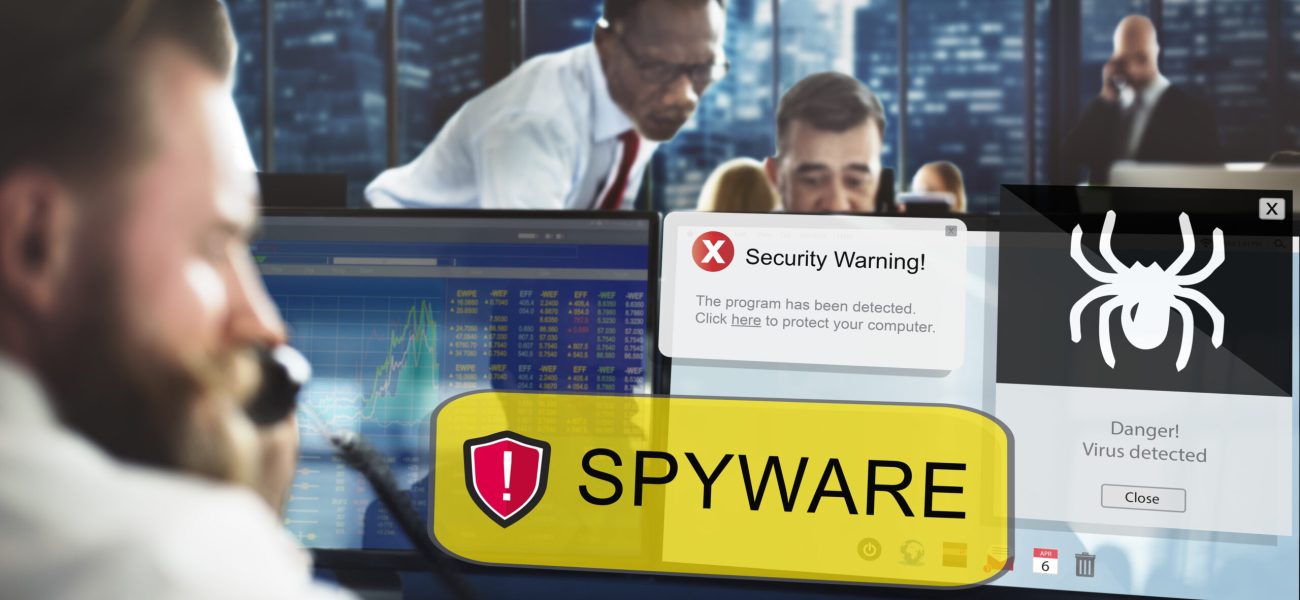 Office workers responding to security warnings on their computer screens about spyware and virus threats.